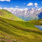 Lacul Koruldi la 2.740 metri, între pajiști verzi și pante line. Un peisaj simplu unde apa reflectă liniștea și amploarea munților din Svaneti.