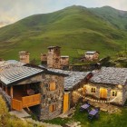 Pensiune din piatră printre colinele din Svaneti, cu lumini calde și turnuri medievale în fundal. Un loc simplu și autentic unde serile curg lent în natură.