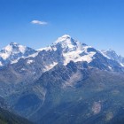 Shkhara (5193 m) se înalță pe cerul limpede, între zăpadă și stâncă. Parte a masivului Zidul Bezengi, domină Caucazul în valea Svaneti din Georgia.