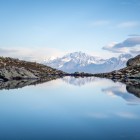 Lacul Udziro, printre roci de altitudine, reflectă vârfurile înzăpezite ale Caucazului. Ape liniștite și cer senin conturează un peisaj simplu și tăcut.