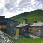 Pensiune tradițională din piatră în Svaneti, între pajiști verzi și Munții Caucaz. Atmosferă autentică, lumini calde la apus și liniștea vieții de munte.