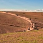 Drum de pământ în deșertul Agafay, printre dealuri aride și spații deschise, cu Munții Atlas în fundal.
