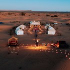 Cort luxury la apus în Merzouga, printre dune, felinare și corturi elegante, pentru a trăi farmecul autentic al Saharei marocane.