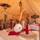 Restaurant elegant într-un cort luxury din Merzouga, cu decor berber, lumini discrete și o atmosferă rafinată în inima Saharei marocane.