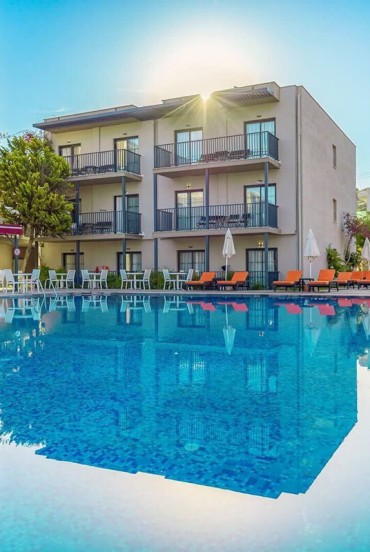 Piscină mare de culoare turcoaz, înconjurată de șezlonguri și terase pentru relaxare: Bodrum Beach Resort oferă o atmosferă perfectă de vară pe litoralul Mării Egee.