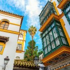 Balcoane elegante în stil andaluz privesc spre străzile istorice ale Sevillei, unde arhitectura maură și tradițiile vechi creează o atmosferă aparte.