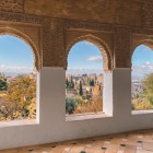 Ferestrele Alhambrei dezvăluie acoperișurile cartierului Albaicín și orașul Granada. O panoramă ce îmbină arta, istoria și farmecul autentic al Andaluziei.