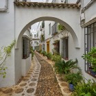 Un arc elegant deschide drumul spre străduțele Cartierului Evreiesc din Córdoba, unde casele albe, pietrele cubice și plantele mediteraneene creează o atmosferă autentică.
