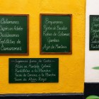 Tablele cu meniuri de la intrarea unei taverne tradiționale din Cádiz prezintă tapas și specialități din fructe de mare, invitând vizitatorii să descopere gastronomia autentică andaluză.