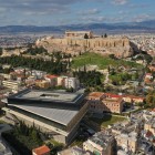 O panoramă spectaculoasă asupra Atenei evidențiază Noul Muzeu al Acropolei și colina sacră cu Partenonul, unde istoria antică se îmbină cu orașul modern.