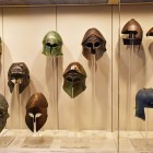 Coifurile din bronz expuse la Muzeul Arheologic din Olympia spun povestea războinicilor greci. Oferite zeilor, păstrează secole de istorie și tradiție.