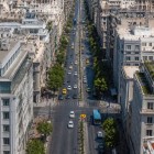 Privită de sus, strada Panepistimiou dezvăluie eleganța Atenei. Bulevardele umbrite și clădirile istorice conduc spre celebra Trilogie Neoclasică a orașului.