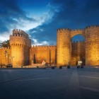 Impresionantele ziduri medievale din Ávila, incluse în Patrimoniul UNESCO, se luminează la apus, încadrând istorica Puerta del Alcázar, simbolul celui mai bine conservat oraș fortificat din Spania.