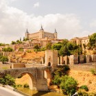 Podul Alcántara traversează râul Tajo la poalele orașului Toledo, dominat de Alcázar și zidurile medievale ce evocă istoria Orașului spaniol al celor Trei Culturi.