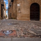 Pavajul de pe Calle Amargura conduce privirea prin centrul istoric al orașului Cáceres, printre fațade vechi din piatră și un portal arcuit ce păstrează atmosfera medievală.