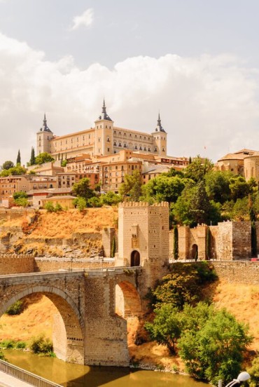 Podul Alcántara traversează râul Tajo la poalele orașului Toledo, dominat de Alcázar și zidurile medievale ce evocă istoria Orașului spaniol al celor Trei Culturi.