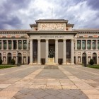Muzeul Prado își întâmpină vizitatorii cu porticul doric al lui Juan de Villanueva: fațada neoclasică, ritmată de coloane și statui, păstrează secole de artă europeană.