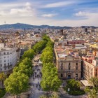 Văzută de sus, La Rambla traversează inima Barcelonei printre platani, clădiri din secolul al XIX-lea și piețe animate, legând Plaça de Catalunya de Port Vell prin centrul istoric.