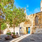 Plaça de Sant Iu păstrează cea mai veche intrare a Catedralei din Barcelona: deschisă în 1298, poarta ogivală a fost accesul principal timp de cinci secole în inima Cartierului Gotic.