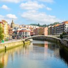 Estuarul Bilbao traversează centrul vechi printre poduri, promenade cu arbori și fațade colorate, conducând privirea spre Mercado de la Ribera, inima vieții urbane.
