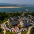 Vedere aeriană asupra Palatului La Magdalena, fostă reședință regală cu arhitectură eclectică, între grădini și pini, cu vedere spre golful Santander și Marea Cantabrică.