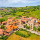 Văzută de sus, Santillana del Mar dezvăluie așezarea dezvoltată în jurul Colegiatei: acoperișuri de teracotă, turnuri medievale și palate din secolele XIV–XVIII, în peisajul verde al Cantabriei.