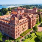 Universitatea Pontificală domină Comillas prin turnuri din cărămidă și detalii neogotice și moderniste, înconjurată de grădini și peisajul verde al coastei cantabrice.
