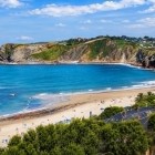 Plaja Comillas se deschide spre Marea Cantabrică, între nisip auriu, ape albastre și faleze verzi, oferind o plimbare panoramică pe spectaculoasa coastă cantabrică.