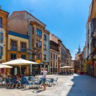Printre bovindourile vitrate de pe Calle Cimadevilla, terasele și magazinele conduc spre turnul Primăriei, ridicat peste poarta medievală către Plaza de la Constitución.
