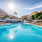 Piscina spațioasă a hotelului de 4 stele Servatur Isora Suites din Puerto de Santiago invită la relaxare printre șezlonguri, palmieri și grădini, sub cerul luminos al insulei Tenerife.