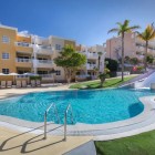 Piscina cu tobogan a hotelului de 4 stele Servatur Isora Suites oferă un spațiu vesel pentru familii, înconjurat de zone verzi, palmieri și clădirile luminoase ale complexului din Puerto de Santiago.