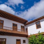 O elegantă curte colonială din San Cristóbal de La Laguna este încadrată de pereți albi, ferestre din lemn și un balcon canarian lung, cu vedere spre un patio intim și luminos.