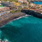 Playa de La Arena din Puerto de Santiago formează un golf cu nisip vulcanic negru, scăldat de ape turcoaz și înconjurat de stânci de lavă și structuri turistice cu vedere la Atlantic.