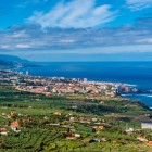 Dincolo de plantațiile fertilei Văi Orotava, privirea ajunge la Puerto de la Cruz, o stațiune animată de pe coasta nordică a insulei Tenerife, încadrată de albastrul intens al Atlanticului.