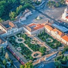 Privit de sus, Palatul Național Queluz apare ca o elegantă reședință regală, încadrată de grădini baroce, partere ornamentale, fântâni și aripi lungi cu acoperișuri roșii distinctive.