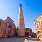 Minaretul Islam Khodja, cel mai înalt din Khiva, domină Itchan Kala prin silueta sa elegantă și zveltă, decorată cu benzi de majolică turcoaz, un simbol al orașului istoric.