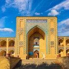 Madrasa Kukeldash, construită în secolul al XVI-lea, întâmpină călătorul cu portalul înalt și logiile pe două niveluri, evocând Buhara de pe Drumul Mătăsii.