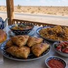 În inima deșertului Kyzylkum, un prânz pe drum oferă plov, samsa, shurpa, pâine non și achichuk, însoțite de tradiționalul ceai verde uzbec.