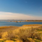 În deșertul Kyzylkum, Lacul Aydar surprinde prin apele sale liniștite, malurile nisipoase și vegetația sălbatică: o oază neașteptată în inima Uzbekistanului.