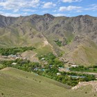 Privit de sus, Ukhum pare o mică oază: casele și copacii urmează cursul apei la poalele munților Nuratau, creând un contrast puternic cu versanții arizi și stâncoși.