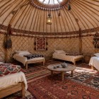 În interiorul iurtei din Aydarkul, structura din lemn, paturile și covorul Shyrdak lucrat manual reflectă moștenirea nomadă a Asiei Centrale.