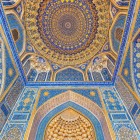 În interiorul Tilla-Kori, privirea urcă spre extraordinarele decorațiuni ale moscheii: albastrul intens, motivele florale și bogatele ornamente aurii creează unul dintre cele mai spectaculoase interioare ale Registanului.