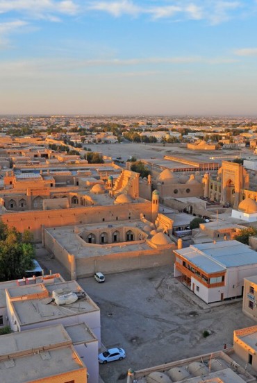 Călătoria părăsește Khiva, cu o priveliște asupra cartierelor istorice și arhitecturii din pământ, marcând începutul lungului transfer prin Khorezm spre Bukhara.