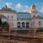 Continuând prin grădină, apare una dintre reședințele complexului, recunoscută după logii, ferestre albastre și forme care îmbină tradiția uzbecă cu gustul european